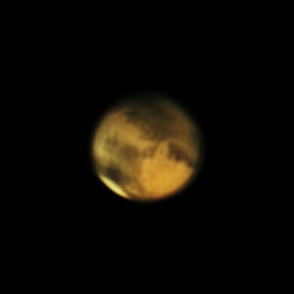 Astrofoto von Mars mit rötlicher Planetenscheibe, Polkappe und dunklen Oberflächenstrukturen